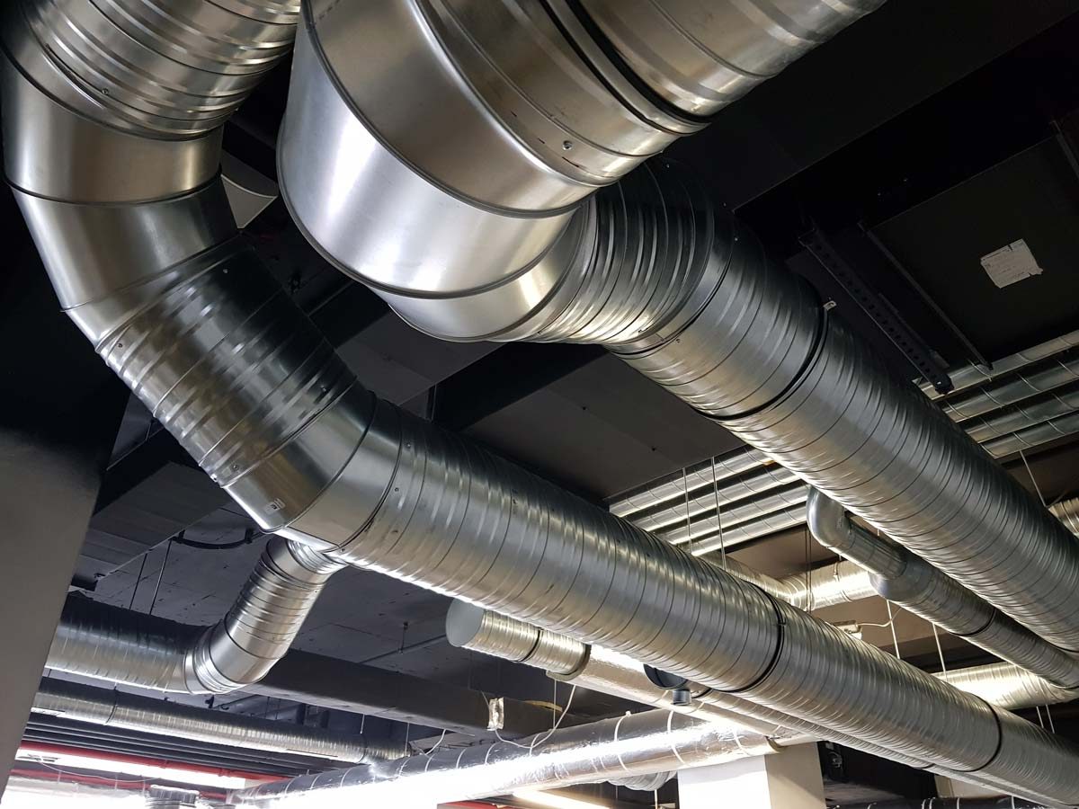 Installation von Wickelfalzrohren für ein Lüftungssystem in einer gewerblichen Deckenkonstruktion.