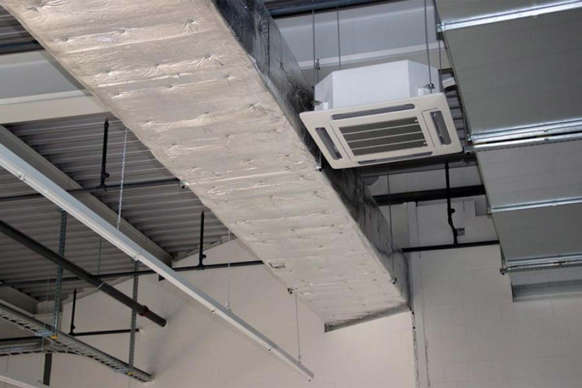 Installation eines isolierten Lüftungskanals und eines Kassettengeräts für die Klimatisierung in einem Gewerbebereich.