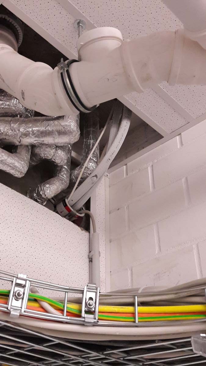 Isolierte Lüftungsrohre, Kältemittelleitungen und Kabeltrassen einer Klima- und Kälteanlage im Deckenbereich installiert.